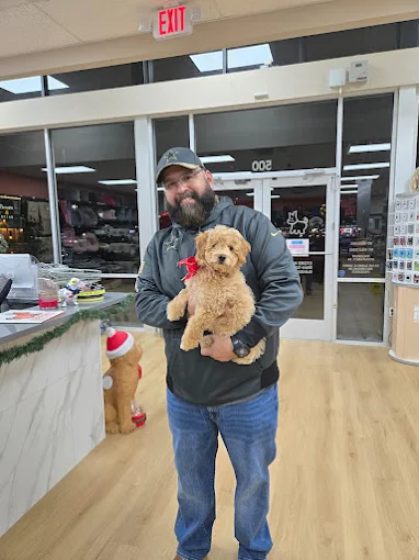 A man holding a curly-coated puppy in a Petland store