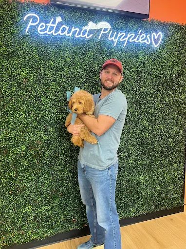 A family with two children holding a puppy in front of a Petland Puppies sign