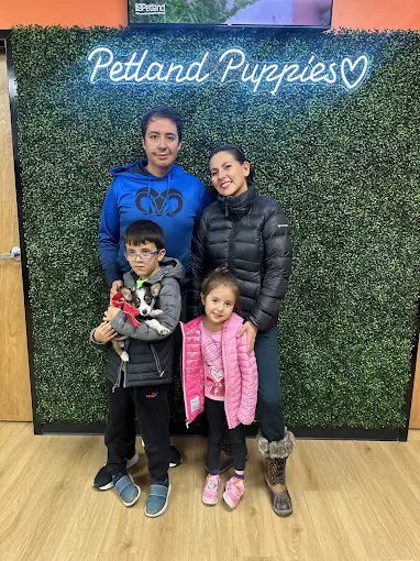A couple holding their puppy in front of a Petland Puppies sign